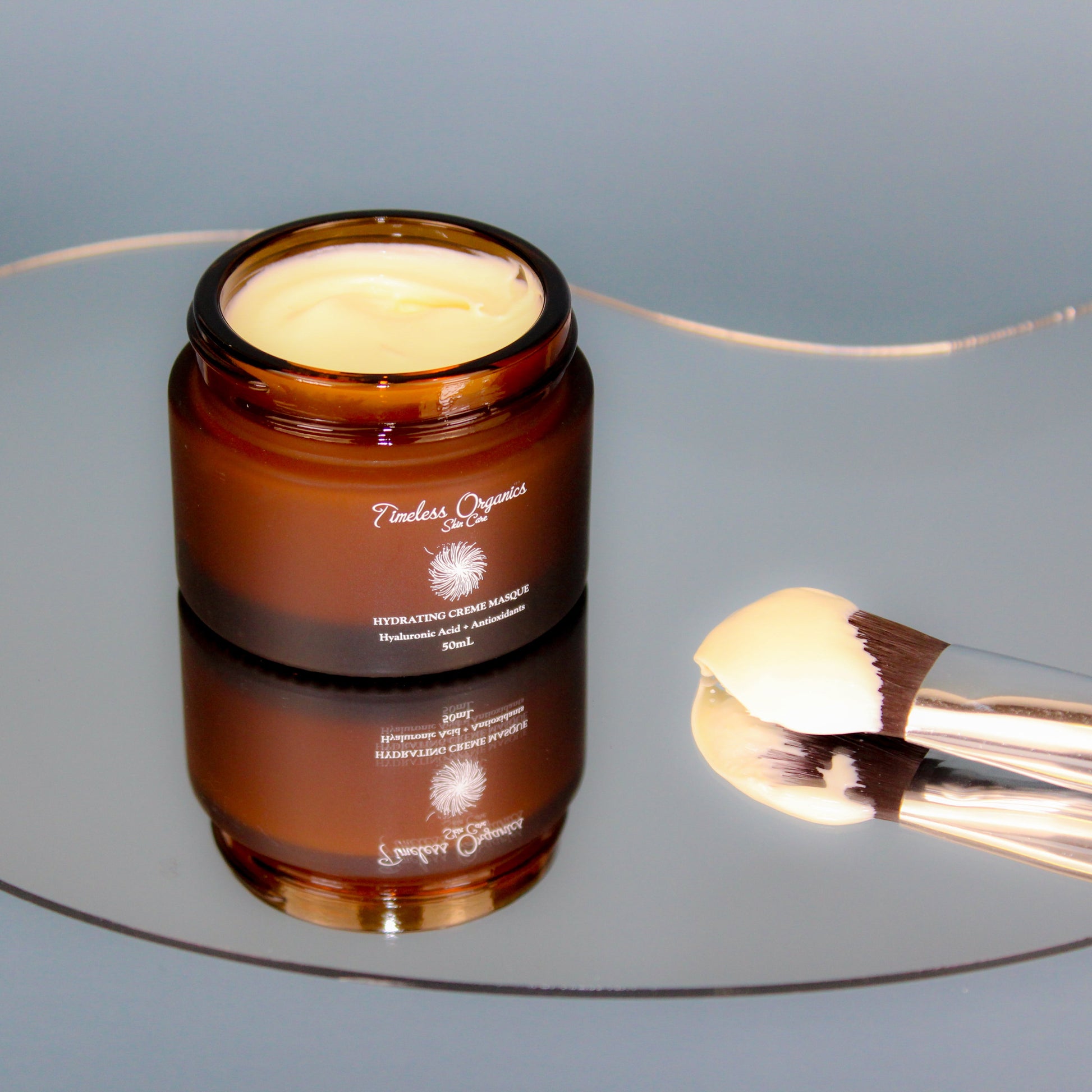 Face cream masque jar with open top, cream inside, and makeup brush in view