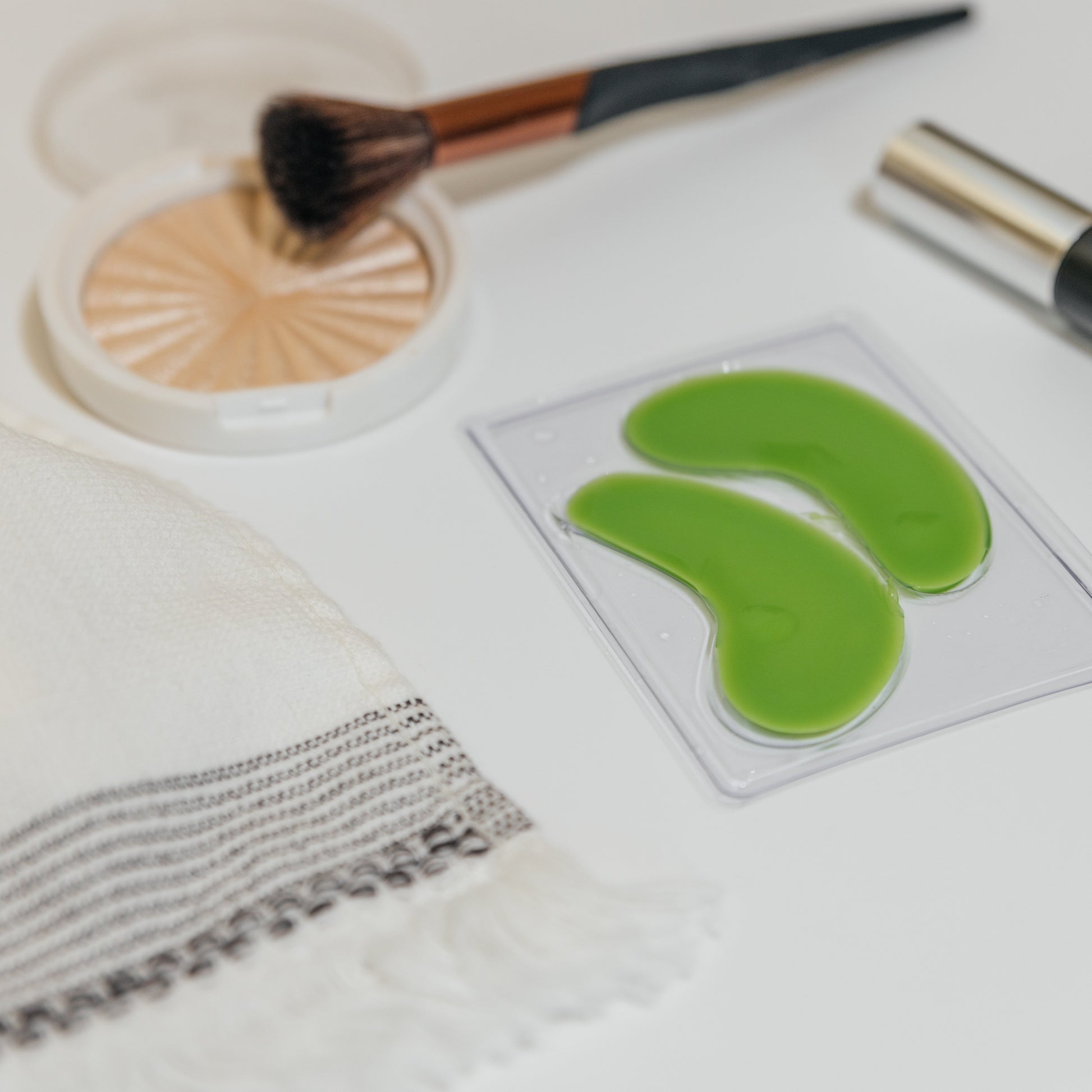 Hydrogel eye masks in clear tray, bright green curved pads for under-eye.