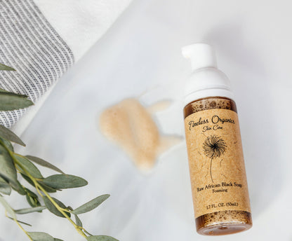 Raw African Black Soap foaming cleanser bottle with white foamy lather beside it.