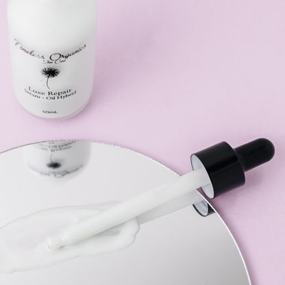 Dropper releasing white serum from luxe repair serum-oil hybrid bottle
